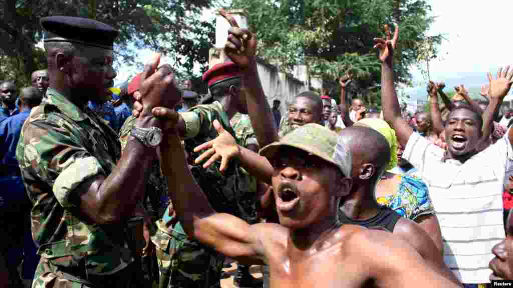 La foule salue des soldats alors qu'elle célèbre après l’annonce de la destitution du président Pierre Nkurunziza par un haut gradé de l’armée à Bujumbura, au Burundi le 13 mai 2015.