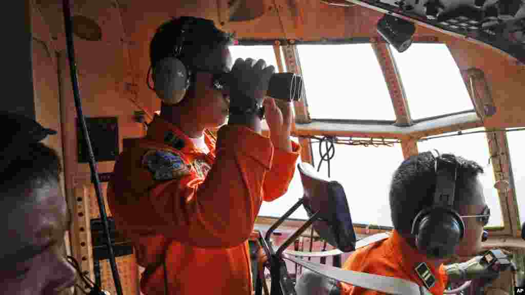 L'équipage de la force aérienne indonésienne dans l'avion Air Force C-130 du 31ème Air Escadro recours des jumelles pour scruter l'horizon pendant une opération de recherche de l'avion d'AirAsie disparu sur les eaux du détroit de Karimata en Indonésie, le 29 décembre 2014.