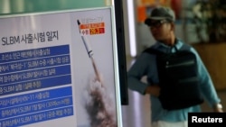 Seorang penumpang kereta api melewati layar televisi di stasiun kereta api Seoul, yang menayangkan berita terkait peluncuran misil dari kapal selam Korea Utara, 24 Agustus 2016 (Foto: REUTERS/Kim Hong-Ji)