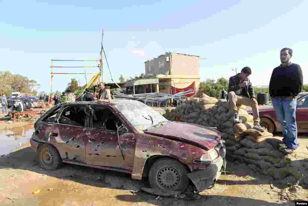 Men look at the scene near a military base 50 km outside Benghazi, after a suicide bomber detonated a truck packed with explosives at an army checkpoint, Barsis, Libya, Dec. 22, 2013. 