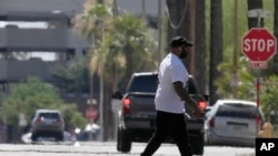 Un peatón cruza una calle mientras olas de calor se elevan desde el pavimento cuando la temperatura alcanza los 104 °F el lunes 17 de junio de 2024 en Phoenix, Arizona.