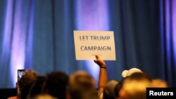 Un partidario del expresidente estadounidense y candidato presidencial republicano Donald Trump sostiene un cartel en la convención nacional del Partido Libertario en Washington, EEUU., el 25 de mayo de 2024.