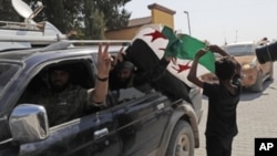 FILE - Members of Turkey-backed Syrian National Army flash the V-sign as they drive back to Turkey near the border between Turkey and Syria, in Akcakale, Sanliurfa province, southeastern Turkey, Oct. 9, 2019.