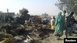 FILE - People return to the site after a bombing attack of an internally displaced persons camp in Rann, Nigeria Jan. 17, 2017.