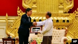 ប្រធានាធិបតីភូមា Thein Sein (រូបស្តាំ) ចាប់ដៃជាមួយអនុរដ្ឋមន្រ្តីក្រសួងការបរទេសរបស់ស.រ.អា. Antony Blinken (រូបឆ្វេង) ខណៈដែលលោកប្រគល់វត្ថុអនុស្សាវរីយ៍កំឡុងកិច្ចប្រជុំរបស់ពួកគេនៅ Presidential Palace កាលពីថ្ងៃទី២១ ខែឧសភា ឆ្នាំ២០១៥ នៅក្រុង Naypyitaw ប្រទេសភូមា។