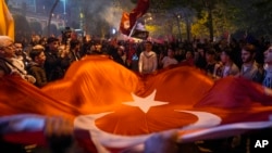 Partidarios del presidente Recep Tayyip Erdogan celebran frente a la sede del AKP (Partido de la Justicia y el Desarrollo) en Estambul, Turquía, el domingo 14 de mayo de 2023. (Foto AP/Khalil Hamra)