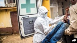FILE- Health workers load a suspected Ebola patient into the back of an ambulance in Freetown, Sierra Leone, Sept. 24, 2014. 