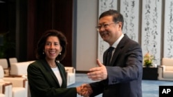 上海市委書記陳吉寧在與來訪的美國商務部長雷蒙多會談前與她握手。（美聯社）