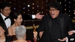Bong Joon Ho, à droite, exultant de joie en recevant le prix de la meilleure images pour "Parasite" aux Oscars le dimanche 9 février 2020 au Dolby Theatre de Los Angeles.(AP Photo / Chris Pizzello)