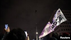 La gente ondea pancartas mientras helicópteros militares vuelan, después de que el presidente surcoreano, Yoon Suk Yeol, declarara la ley marcial, en Seúl, Corea del Sur, el 4 de diciembre de 2024.