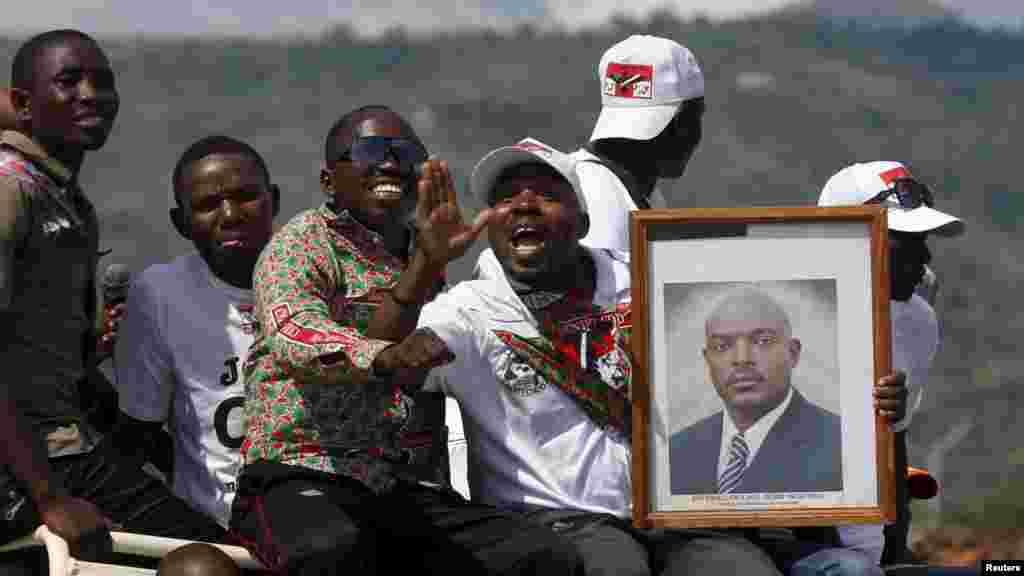 Des partisans du président du Burundi, Pierre Nkurunziza, jonchés sur un véhicule avec son effugie en mains, attendent le passage de son convoi dans la capitale, dans une rue à Bujumbura, après un coup d'Etat manqué au Burundi, le 15 mai 2015.