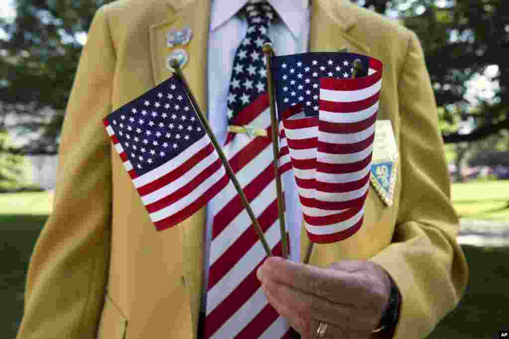 Navy veteran William Englert passes out U.S. flags to the crowd attending Memorial Day ceremonies at Arlington National Cemetery, May 25, 2015. 