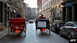 Dua kereta kuda melintas di jalan Old Montreal, Quebec, Kanada pada 22 Desember 2019. (Foto: AFP)