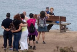 Tourists wait in line to sit on a bench on a cliff overlooking the Cantabrian sea in Loiba, northwestern Spain, Aug. 2, 2020.