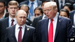 Le président russe Vladimir Poutine, à gauche, et le président américain Donald Trump discutent lors de la séance de photos de famille en marge du sommet de la Coopération économique Asie-Pacifique (APEC) à Danang, Vietnam, 11 novembre 2017.
