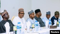 Le président nigérian Muhammadu Buhari est accompagné du gouverneur de l'Etat du Plateau, Simon Lalong, et des officiels lors de sa visite, le 26 juin 2018.