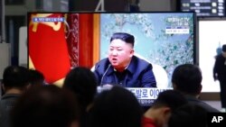 Orang-orang menyaksikan program berita yang menyajikan foto pemimpin Korea Utara, Kim Jong Un, di layar televisi yang terpasang di Stasiun Kereta Api Suseo, di Seoul, Korea Selatan, 25 Maret 2021. 