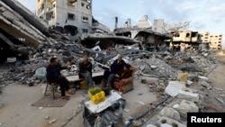 Palestinians sit near the ruins of a house destroyed in the Israeli military offensive in Khan Younis in the southern Gaza Strip, Nov. 29, 2024.