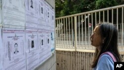 资料照片：一名行人在香港观看警方为以涉及违反国安法的罪名对八名居住在美国、英国、加拿大和澳大利亚发出的通缉令。(2023年7月14日)