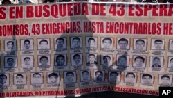 ARCHIVO - Familiares y amigos de los 43 estudiantes de Ayotzinapa desaparecidos marchan con un cartel con las fotos y el nombre de los jóvenes en el noveno aniversario de su desaparición, en Ciudad de México, el 26 de septiembre de 2023. 
