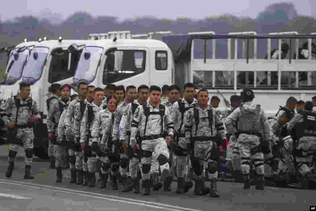 Mexican National Guards prepare to board an aircraft at the International Airport in Merida, Mexico to travel north to reinforce the country's border with the United States.
