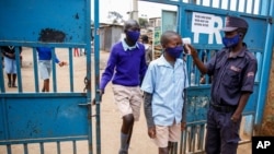 Schoolchildren have their temperature taken as they arrive at the Olympic Primary School in Kibera, one of the capital Nairobi's poorest areas in Kenya, Oct. 12, 2020.
