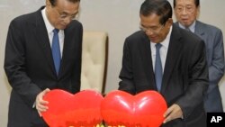 China's Premier Li Keqiang, left, pulls a symbol of China-Cambodia Heart Journey, together with his Cambodian counterpart Hun Sen, center, during a signing ceremony at Peace Palace in Phnom Penh, Cambodia, Thursday, Jan. 11, 2018. Cambodia and China on Th