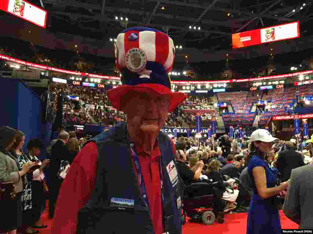 Couvert d'un chapeau rappelant l'oncle Sam, un participant affiche des insignes de l’état de Montana et de l’ancien président Bush à Cleveland, Ohio, le 18 juillet 2016. (VOA/Nicolas Pinault).
