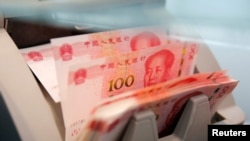 Des billets chinois de 100 yuans dans une machine de comptage de la une succursale d'une banque commerciale à Pékin, en Chine, le 30 mars 2016. 