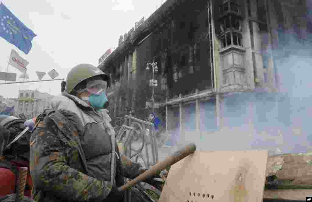 An anti-government protester stands behind a barricade during clashes with riot police in Independence Square, Kyiv, Ukraine, Feb. 19, 2014.