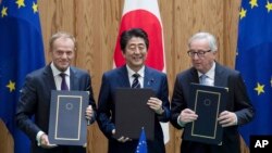 Perdana Menteri Jepang Shinzo Abe (tengah), Presiden Dewan Uni Eropa Donald Tusk (kiri), dan Presiden Komisi Uni Eropa Jean-Claude Junker berpose setelah menandatangani kontrak, di kantor perdana menteri Jepang di Tokyo, Selasa, 17 Juli 2018.