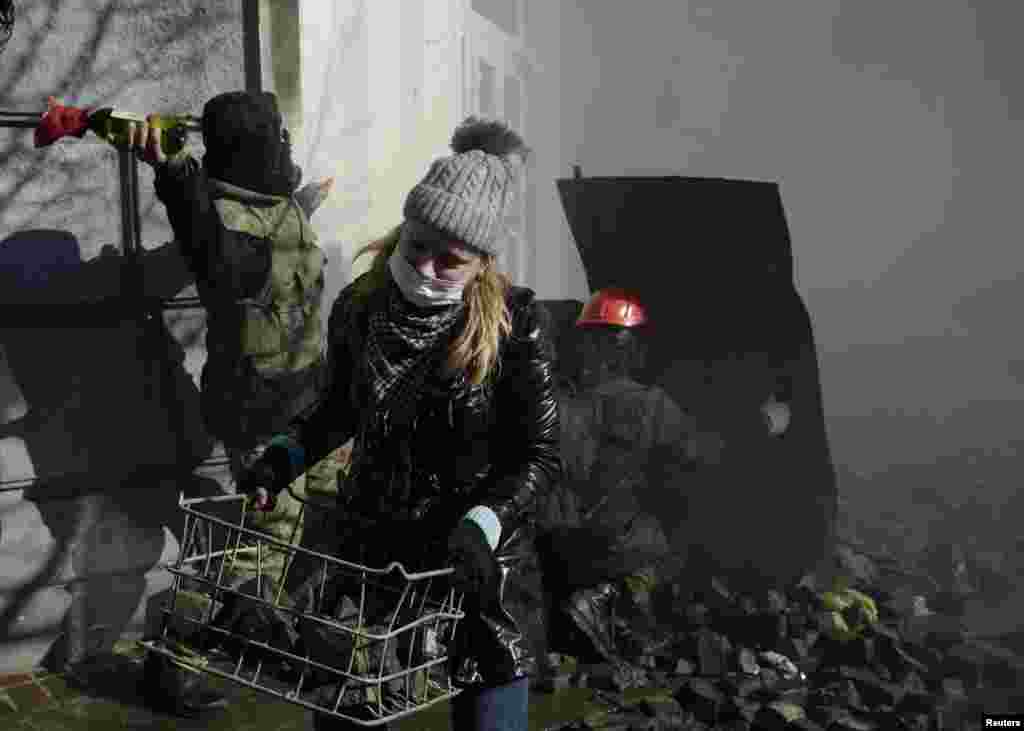A woman carries stones during clashes between anti-government protesters and Interior Ministry members, Kyiv, Feb. 18, 2014.