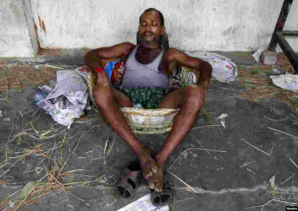 A laborer takes a nap in a basket at a wholesale vegetable market during a heat wave in Kolkata, May 25, 2015. 