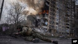 Український правоохоронець перед будівлею, яку уразила російська авіація в Авдіївці. Березень 2023 року. Фото: AP/Євгеній Малолетка