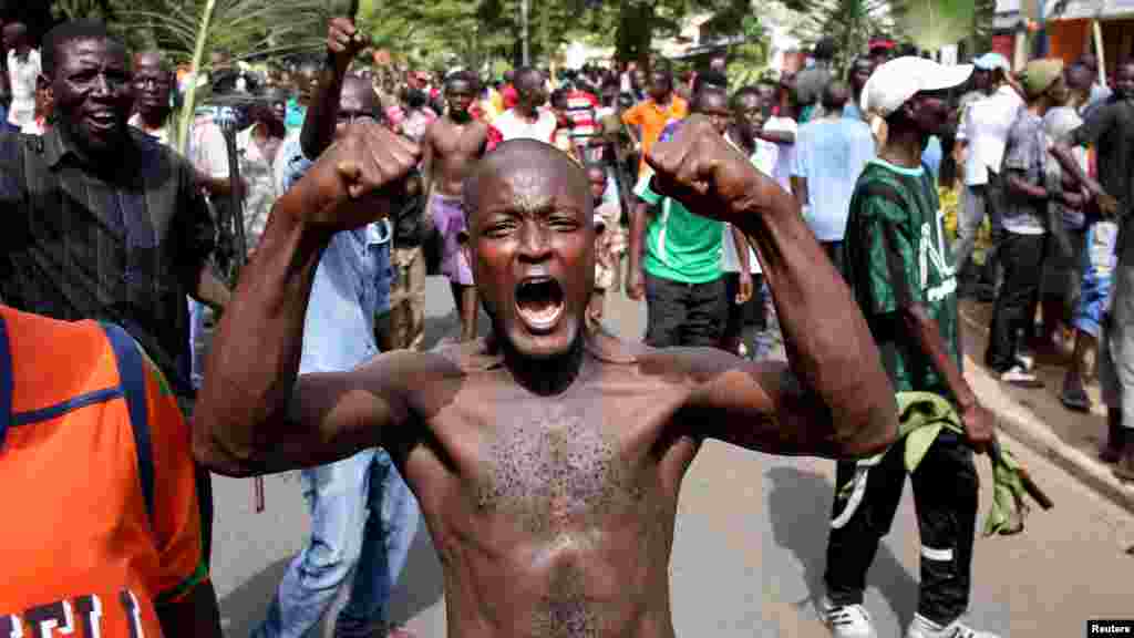 Un homme fait un geste de victoire à côté de la foule en liesse après l’annonce de la destitution du président Pierre Nkurunziza par un haut gradé de l’armée à Bujumbura, au Burundi le 13 mai 2015.
