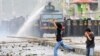 FILE - Indonesian students react as a police water-cannon truck sprays water to disperse a rally commemorating the International Anti-Corruption Day that turned violent in Makassar, South Sulawesi, Indonesia, December 2013.