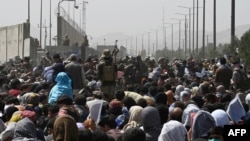 Afghans gather on a roadside near the military part of the airport in Kabul, Aug. 20, 2021, hoping to flee from the country after the Taliban takeover of Afghanistan.
