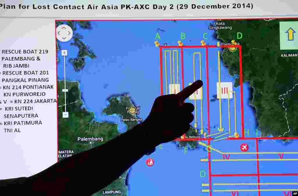 Un membre de l'Agence nationale indonésienne de recherche et de sauvetage (Basarnas) pointe un doigt à une carte d'une zone de recherche lors d'un briefing avant une opération de recherche et sauvetage d el'avion d'AirAsia disparu, décembre . 29, 2014.