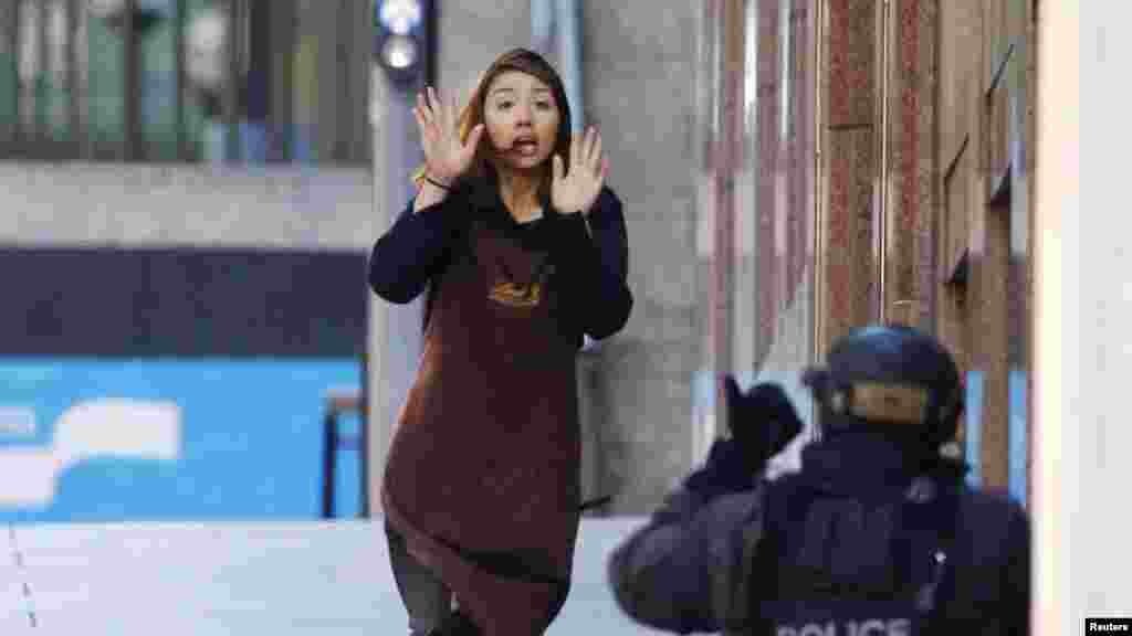 A hostage runs toward a police officer outside Lindt cafe, where other hostages are being held, in Martin Place in central Sydney, Australia, Dec. 15, 2014.