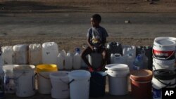 Un petit garçon fait la queue pour obtenir de l'eau gratuite de la municipalité, à Senekal, Afrique du Sud, le 7 janvier 2016. (AP Photo/Denis Farrell)