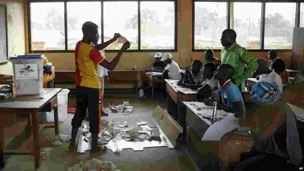 Des responsables des élections contrôlent la conformité au cours du dépouillement des bulletins de vote après la fermeture des bureaux, au deuxième tour de l'élection présidentielle à Bangui, en République centrafricaine, 14 février 2016.