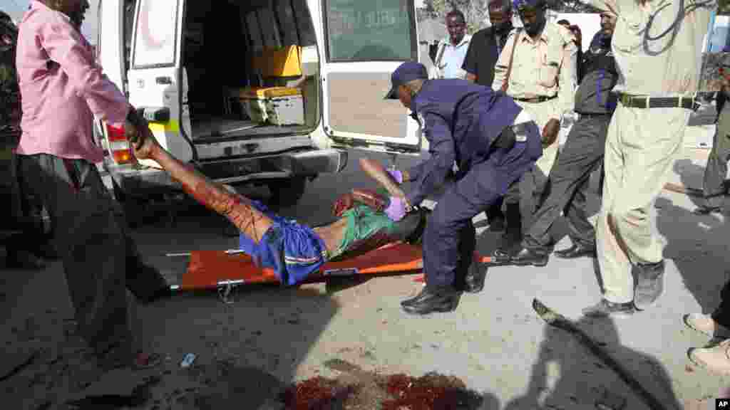 Des policiers transportent le suspect blessé dans l'attentat à l'extérieur de l'académie de la police de Mogadiscio, en Somalie, le mercredi 9 mars 2016.