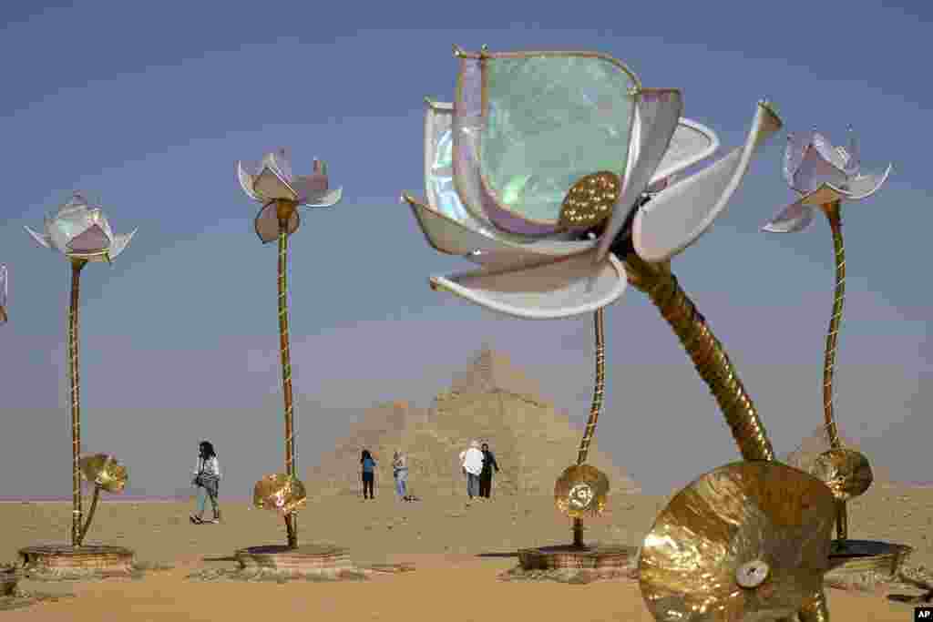 Visitors walk past the "Padma/Pulse and Bloom" art installation of Indian artist Shilo Shiv Suleman during the "Forever Is Now" contemporary art exhibition at the historical site of the Giza Pyramids, on the outskirts of Cairo, Egypt.