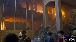 Pasukan pro-Gaddafi dan warga Tripoli mengamati bangunan yang baru dihantam serangan udara NATO (17/5).