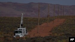 A crew with the Navajo Tribal Utility Authority installs power poles, Oct. 9, 2024, on the Navajo Nation in Halchita, Utah.
