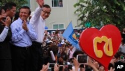 Opposition Cambodia National Rescue Party (CNRP) leader Sam Rainsy, right, accompanied by his party's Vice President Kem Sokha, second from right, waves to his party supporters during a public forum of the July 28 election result, in Phnom Penh, file photo.