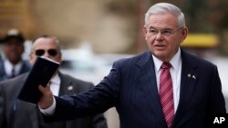 U.S. Sen. Bob Menendez waves at reporters before entering the Martin Luther King Jr. Federal Courthouse for his federal corruption trial, Nov. 16, 2017, in Newark, N.J.