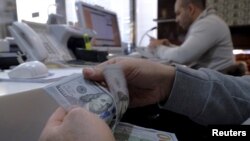 FILE - A money changer counts out U.S. dollars for a customer in Tehran's business district, Iran, Jan. 20, 2016. 