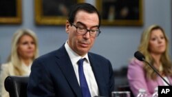 美國財政部長努欽(Steven Mnuchin)在華盛頓國會山作證時閱讀手機上的一條信息（2020年3月11日）。