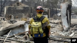 Seorang petugas pemadam kebakaran memeriksa kawasan yang terbakar dalam kebakaran lahan di Keswick, California, 29 Juli 2018.